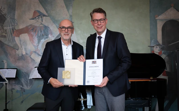 Color photo of two people holding a certificate looking into the camera