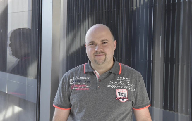 Color photograph of a person facing the camera wearing a dark polo shirt