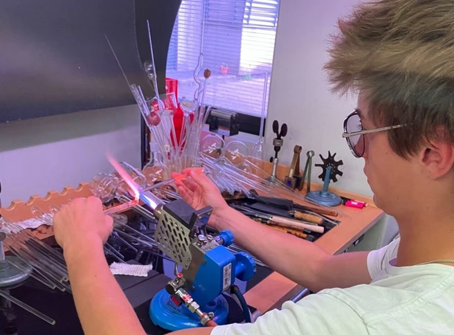 Color photo of a person working with glass blowing materials
