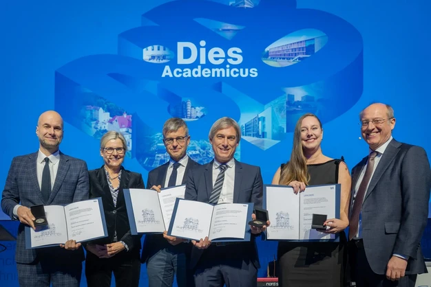 Color photo of a 6 people smiling into the camera, some holding award certificates